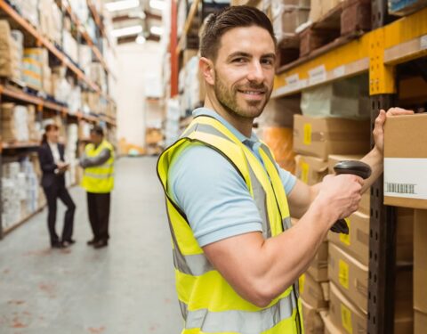 warehouse-worker-scanning-box-while-smiling-camera